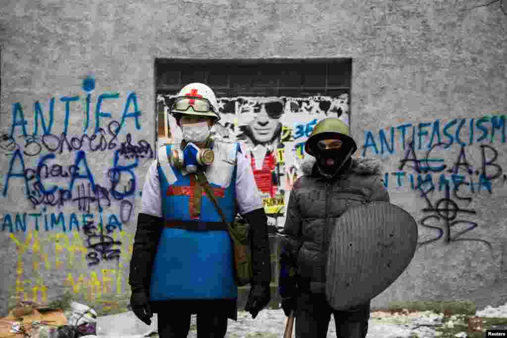 A medic of the antigovernment protest camp (left) poses for a portrait with his security guard at the barricades near the site of clashes with riot police in Kyiv on January 28. (Reuters/Thomas Peter)