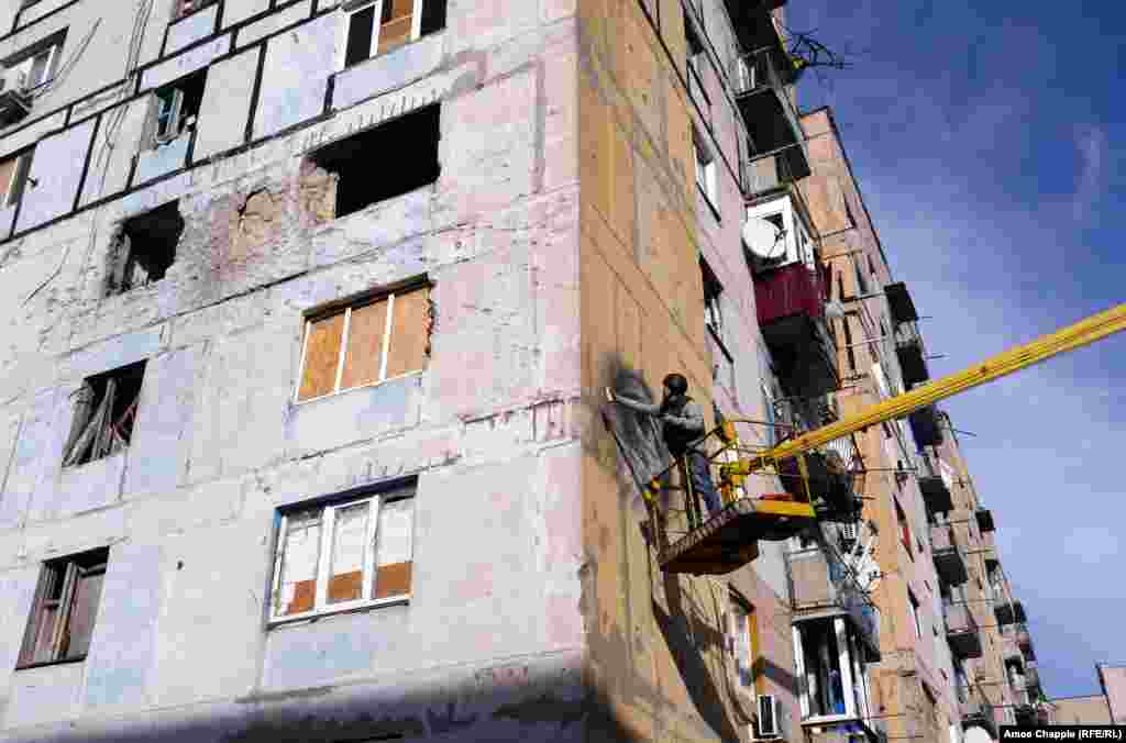 Damage from an artillery or tank round above where Van Helten works. The building has stood empty since 2014, after a Grad (Hail) rocket landed in one of the apartments, killing two civilians inside.&nbsp;