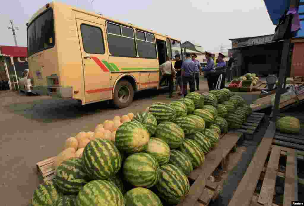 Police officers escort detained migrant workers to a police bus following an unannounced document check at a market in the Siberian city of Krasnoyarsk in August 2013.&nbsp;