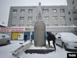 A man cleans the statue of Lenin in Novosibirsk after it was painted in the colors of the Ukrainian flag.