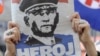 Një grua mban një gazetë me portretin e gjeneralit kroat, Ante Gotovina, ku shkruan “hero”, ndërsa ndjek transmetimin e drejtpërdrejtë televiziv të aktgjykimit ndaj tij. Zagreb, 15 prill 2011.