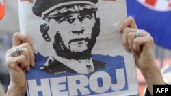 Žena drži novinu s likom bivšeg hrvatskog generala Ante Gotovina dok sluša izricanje presude, 15. april 2011.