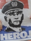 Një grua mban një gazetë me portretin e gjeneralit kroat, Ante Gotovina, ku shkruan “hero”, ndërsa ndjek transmetimin e drejtpërdrejtë televiziv të aktgjykimit ndaj tij. Zagreb, 15 prill 2011.
