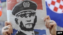 In Zagreb, a woman holds a newspaper with a portrait of General Ante Gotovina over the word "hero" as she watches the verdict in The Hague.