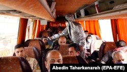 A member of Iranian red crescents checks bus passengers for possible coronavirus Covid 19 symptoms, as police blocked Tehran to Alborz highway to check every car following order by Iranian government, March 26, 2020