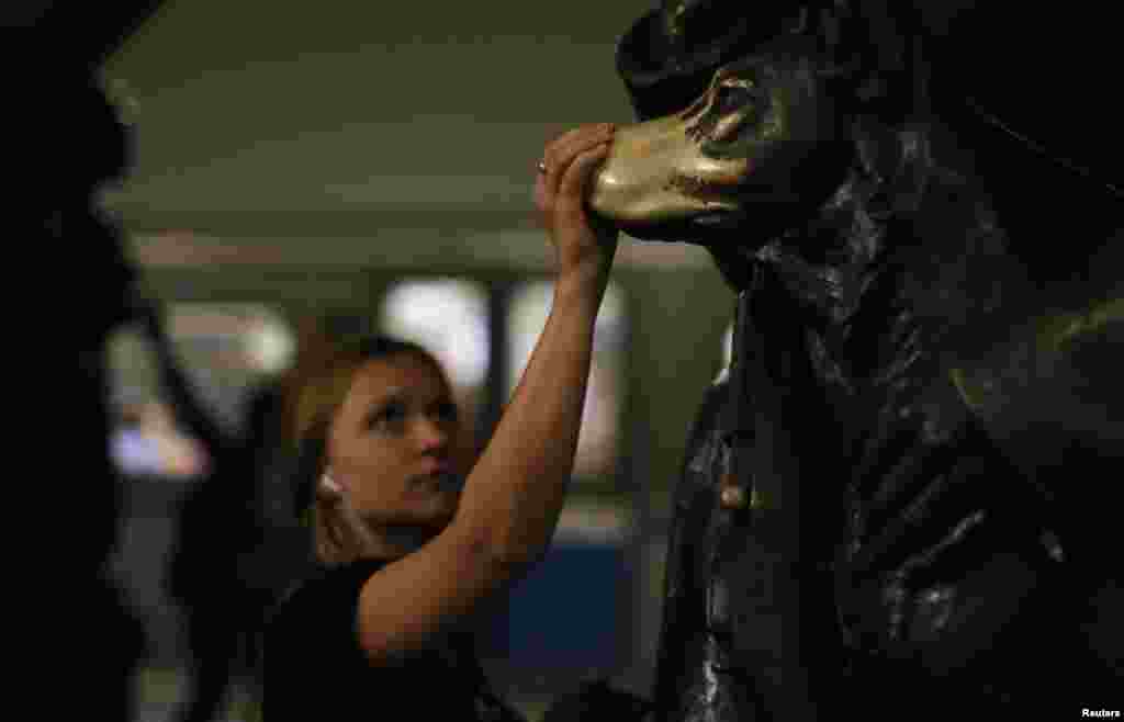 A woman touches the nose of the so-called &quot;lucky dog&quot; statue at the Ploshchad Revolyutsii station.
