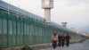 Работници преминават покрай едно от съоръженията, известни като центрове за обучение и получаване на квалификации в населяваната от уйгури китайска провинция Синцзян.