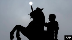 The sun is seen through the fog behind a monument depicting Alexander the Great in Skopje, December 18, 2013