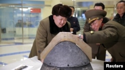 Лидеру Северной Кореи Ким Чен Ыну (слева) показывают образец баллистической ракеты. 