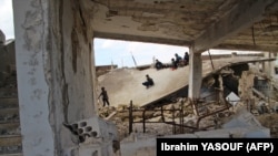 Syrian children slide on the collapsed roof of a school which was hit by bombardment in the district of Jisr al-Shughur, in the west of the mostly rebel-held Idlib province, on January 30, 2019.