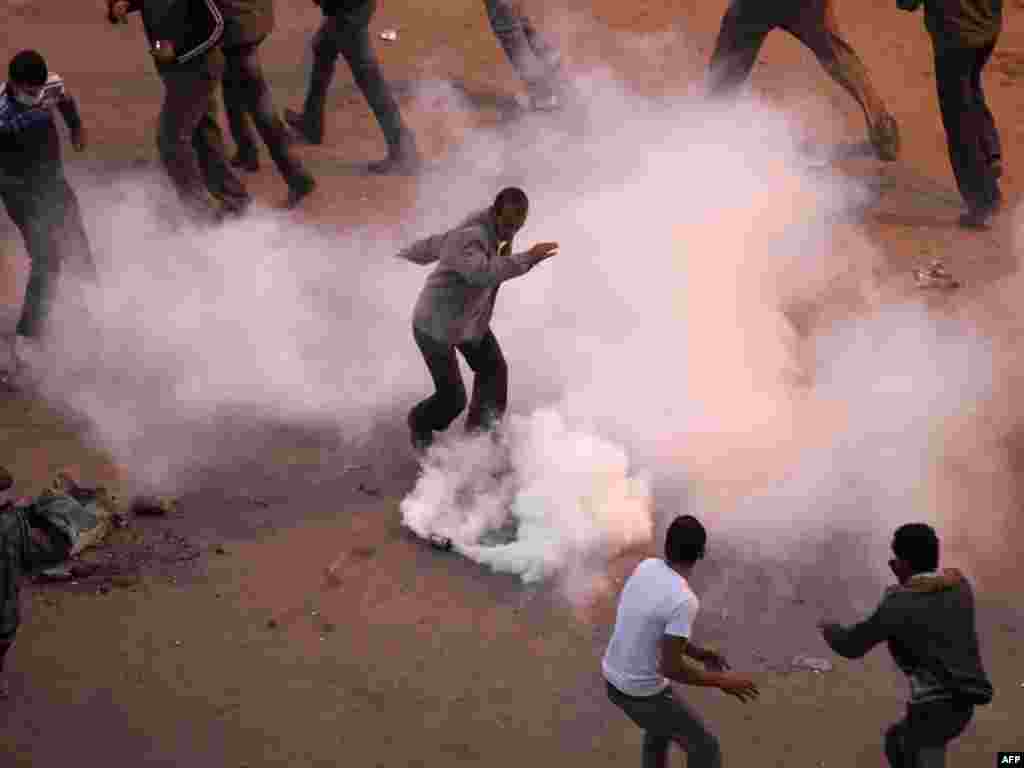 Anti-government demonstrators remove a tear gas canister thrown by police during clashes January 27.