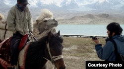 China -- RFE/RL Correspondent Janyl Jusupjan speaks with a trader at Kara-kol. Local Kyrgyz offer horses and camels for riding and sell small gifts to tourists. May 16, 2011. 