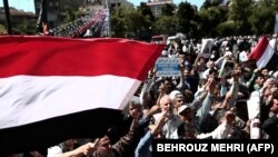 Iranian protesters chant slogans as they hold national flags of Yemen during a demonstration in Tehran on May 8, 2015.