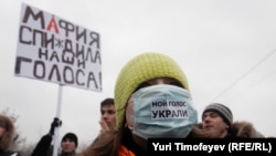 The rallies in Moscow on December 10 protesting the election results were said to be the largest demonstrations since the collapse of the Soviet Union. Her mask says "They stole my vote." The banner says "The Mafia Stole Our Vote."