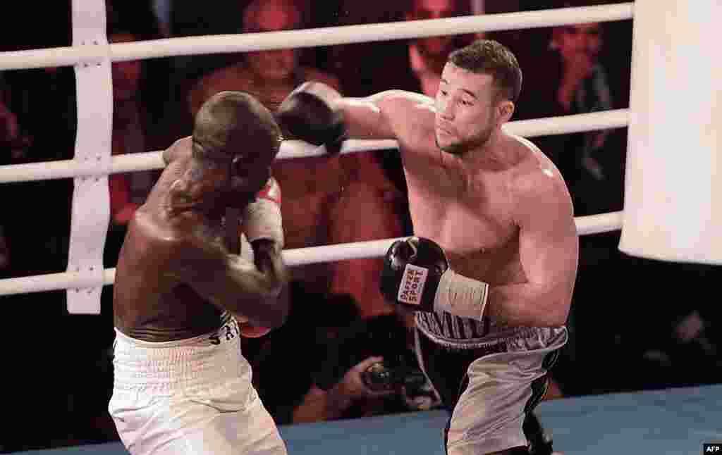 OCTOBER 30, 20212 -- Afghan-German boxer Hamid Rahimi (right) throws a punch at Tanzania&#39;s Said Mbelwa in Afghanistan&#39;s first professional bout in 30 years. Rahimi won the World Boxing Organization&#39;s unclaimed intercontinental middleweight championship by TKO in the seventh round before some 1,500 spectators in Kabul. (AFP/Massoud Hossaini)