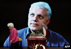 A mourner pays tribute near the casket and portrait of Sheremet at the memorial service.