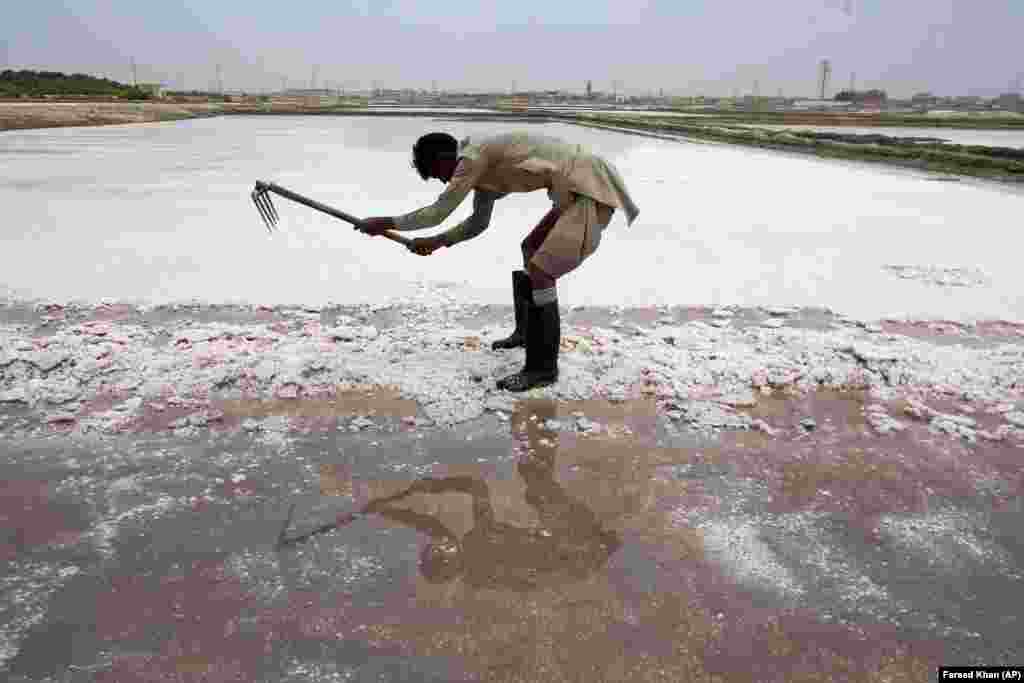 Laborer Abdul Sattar, 45, of Pakistan collects sea salt at a coastal area of Karachi. Sattar earns on average 800 Pakistani rupees ($5) per day for his work. (AP/Fareed Khan)