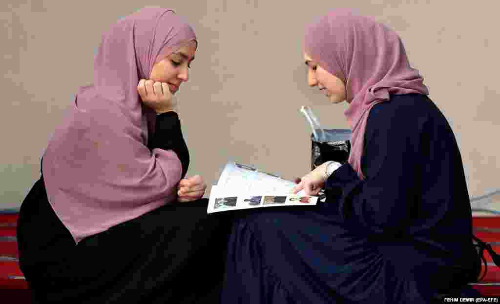 Two Muslim girls read a magazine in front of the Gazi Husrev-beg Mosque in Sarajevo, Bosnia-Herzegovina, on May 21.