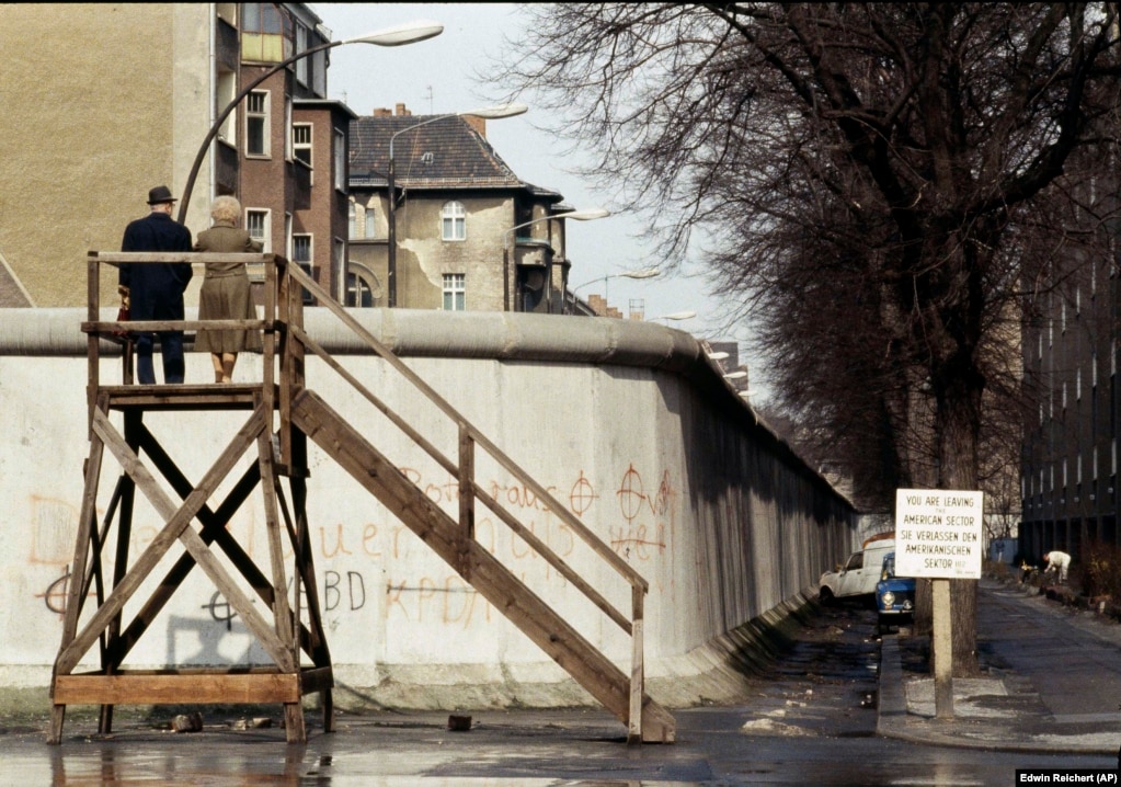 Një çift duke shikuar përtej murit në Berlinin Lindor në prill 1983. Salter tha se testimi i barrierave kundër automjeteve ishte vetëm një pjesë e përpjekjes së gjerë kërkimore dhe zhvillimore për t&#39;i bllokuar njerëzit brenda shtetit policor. Vetë struktura e Murit të Berlinit, thotë ai, u sprovua &quot;për rezistencën e tij ndaj sulmeve me automjete, eksplozivë dhe se si do t&#39;u rezistonte fenomeneve natyrore, si p.sh. larja nga uji gjatë reshjeve të mëdha&quot;.