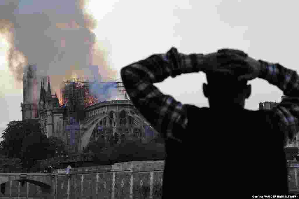 A man watches Notre Dame Cathedral burn on April 15, 2019.