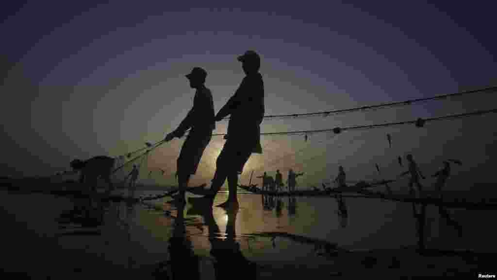 Pakistani fishermen are silhouetted against the setting sun as they pull in their nets to retrieve their catch at Karachi&#39;s Clifton Beach on May 23. (Reuters/Athar Hussain)&nbsp;