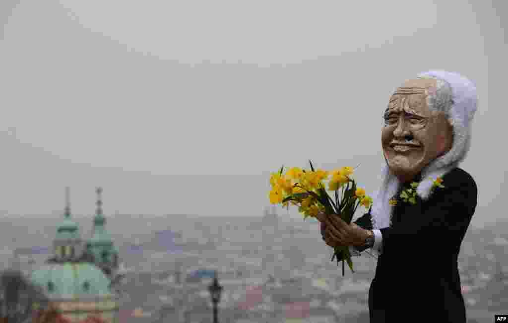A man wearing a mask of Czech President Vaclav Klaus holds flowers during a march in Prague celebrating the end of his presidency. (AFP/Michal Cizek)