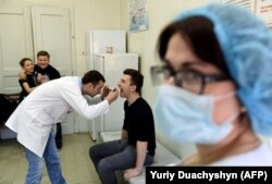 A doctor examines a teenager prior to a vaccination against measles in the Ukrainian city of Lviv. file photo)