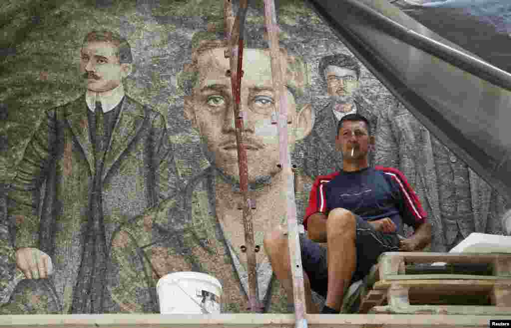 A worker smokes a cigarette in front of a mosaic with an image of Gavrilo Princip, the Bosnian-Serb assassin whose actions helped precipitate the outbreak of World War I, in Andricgrad village near Visegrad in Bosnia-Herzegovina on June 23. (Reuters/Djordje Kojadinovic)