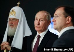 Președintele rus Vladimir Putin (mijloc), Patriarhul Kiril (stânga) și Vladimir Medinski (dreapta), în vizită la Moscova pentru o expoziție despre al Doilea Război Mondial, cunoscut în Rusia drept Marele Război Patriotic.