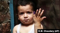 A Pakistani child shows his finger, which was marked after receiving the polio vaccine, in Lahore on April 24.