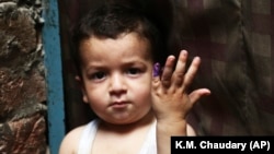 A Pakistani child shows his marked finger after receiving the polio vaccine in Lahore, Pakistan, on April 24.