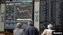 Traders watch electronic boards at the stock exchange in Madrid on June 11.