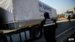 A worker stands as a Syria-bound truck, loaded with humanitarian aid, gets ready to leave a UN transhipment hub near the Turkish-Syrian border. (file photo)