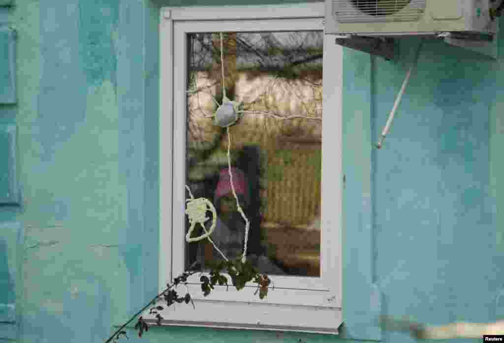 A girl looks out of a damaged window in an area between separatist forces and Ukrainian government troops in the village of Kominternove, northeast of the port city of Mariupol, Ukraine. (Reuters/Alexander Ermochenko)