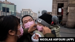Люди в защитных масках на железнодорожном вокзале в Пекине. 27 января 2020 года.
