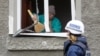 A member of the OSCE walks past a local resident, who removes debris inside a house damaged during recent fighting between Ukrainian forces and Russia-backed separatists in Luhansk in eastern Ukrainie. 