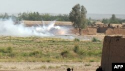 Civilians look on as a mortar explodes outside a military base. Civilian casualties have soared in Afghanistan this year.