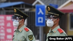 Офицеры военизированного подразделения полиции в Китае в масках и защитных очках на входе на закрытый продовольственный рынок. Пекин, 13 июня 2020 года. 