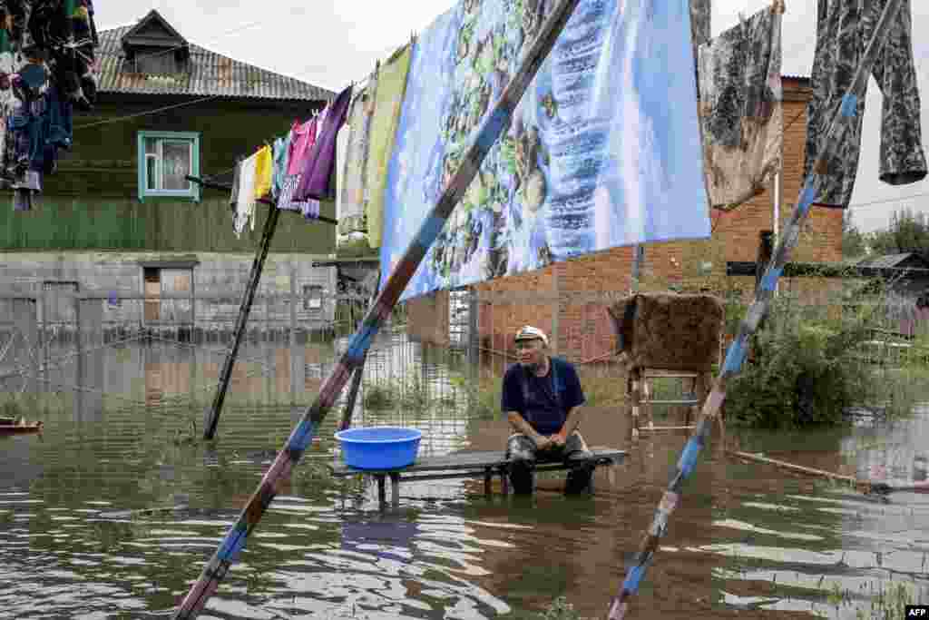 A man sits by a flooded street in the village of Bolshoi Ussuriysky near Khabarovsk.
