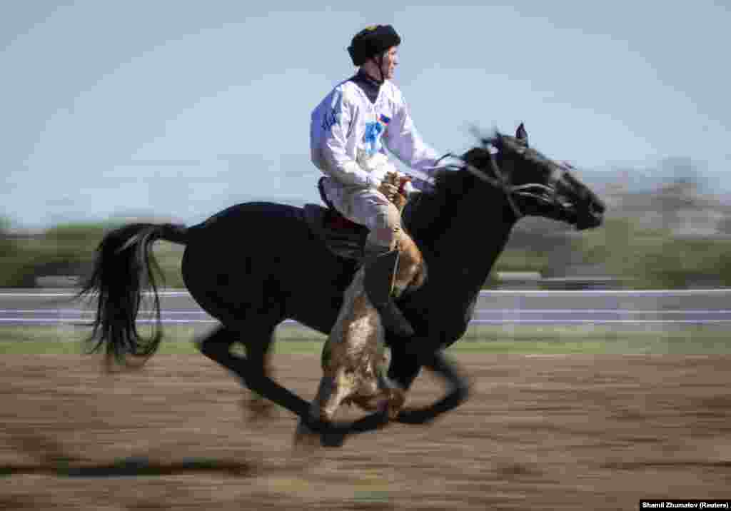 A rider from Russia&#39;s team gallops with the goat&#39;s carcass during a match against Kazakhstan.