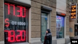 Russia -- A Russian woman passes a currency exchange office where electronic information panels display exchange rates of ruble to Euro, in St. Petersburg, January 24, 2016