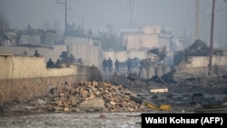 Afghan security forces gather at the site of a powerful truck-bomb attack a day after it detonated near a foreign compound in Kabul on January 15.