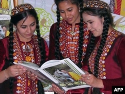 Туркменские девушки рассматривают книгу о туркменской породе лошадей с президентом Бердымухамедовым на обложке. Ашгабат, 12 апреля 2011 года.