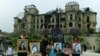 Children displaying photos of war victims stand in front of the damaged Darul Aman Palace just outside of Kabul, which was one of the area's many casualties, before its reconstruction.