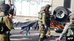 
Израильские военные несут тело застреленного палестинца, напавшего с ножом на сотрудника погранслужбы Израиля, 29 октября 2015 года