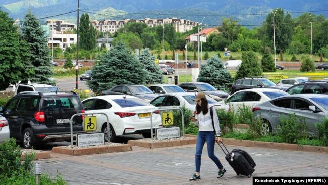 Алматыдағы көлік тұрағының жанынан өтіп бара жатқан адам. Көрнекі сурет.