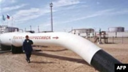 Рабочий на фоне нефтепровода, поставляющего нефть с месторождения Тенгиз.