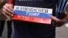 Američki demonstrant drži transparent sa bojama ruske zastava na kojem piše Rorabaher, Tramp i Putin