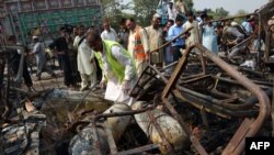 Volunteers search the wreckage of a passenger van after a bomb explosion in Peshawar on October 2, 2014.