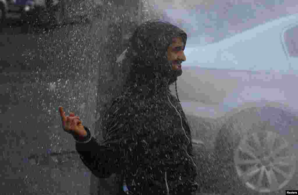 A demonstrator in Diyarbakir gestures as riot police use a water cannon to disperse the crowd during a protest against the arrest of the Kurdish-dominated Turkish city's two joint mayors for alleged links to terrorism. (Reuters/Sertac Kayar)